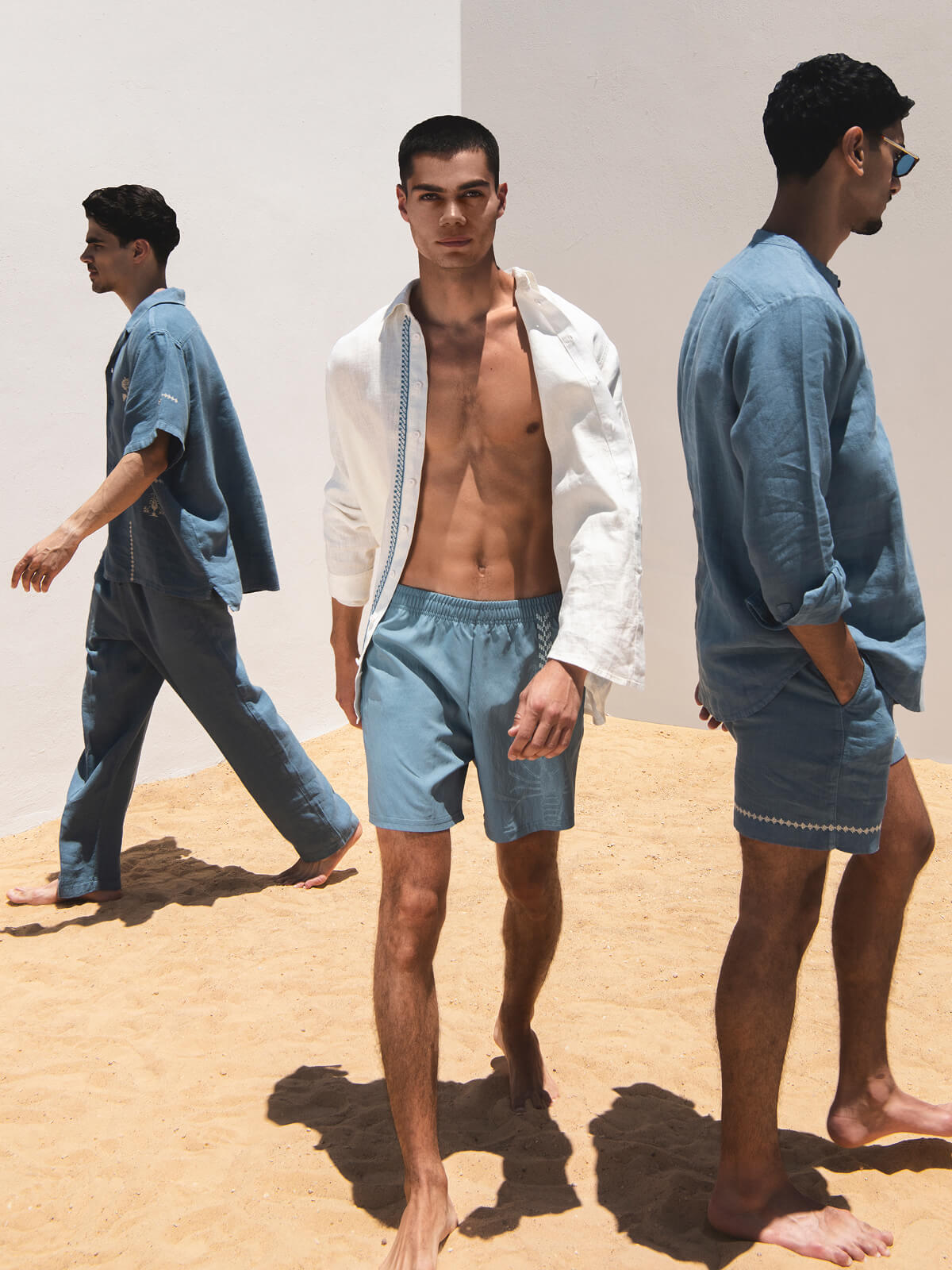 Three male models wearing Arak Studio’s summer linen collection walking barefoot in a desert-inspired setting.